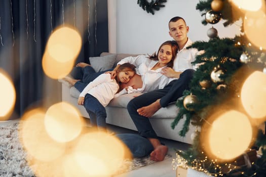 With Christmas tree. Happy family celebrating holidays indoors together.
