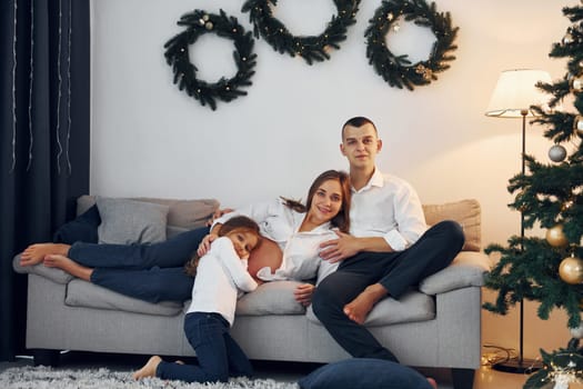 With Christmas tree. Happy family celebrating holidays indoors together.