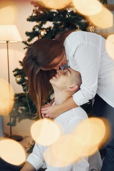 Embracing each other. Lovely couple celebrating holidays together indoors.