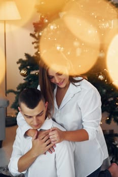 Embracing each other. Lovely couple celebrating holidays together indoors.