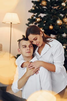 Embracing each other. Lovely couple celebrating holidays together indoors.