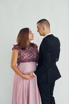 Couple in formal clothes standing in the studio with white background.