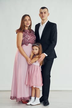 Happy couple with little daughter is standing in the studio.