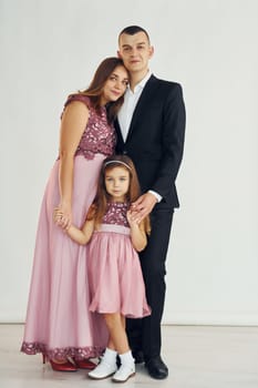 Happy couple with little daughter is standing in the studio.