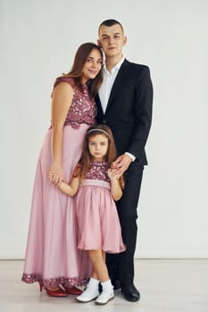 Happy couple with little daughter is standing in the studio.