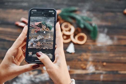 Woman holding phone. Christmas background with holiday decoration.