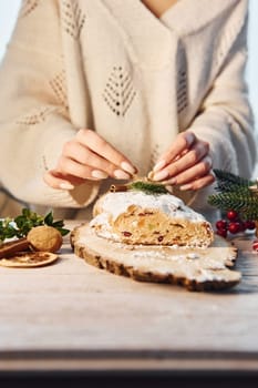 Woman standing and decorating stollen that is on the holiday christmas table.