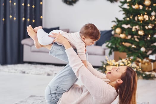 Having fun. Mother with her little daughter is indoors at home together.