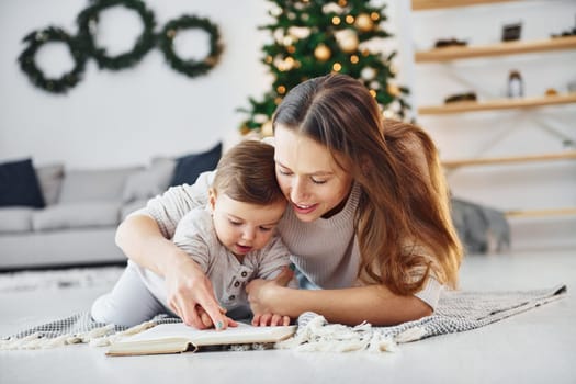 Sitting on the ground. Mother with her little daughter is indoors at home together.