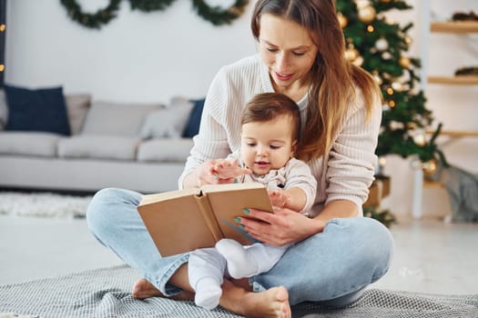 Sitting on the ground. Mother with her little daughter is indoors at home together.