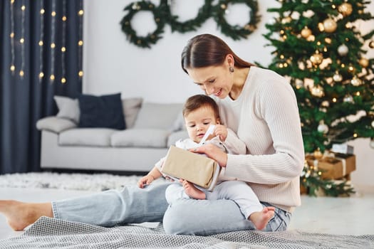 Sitting on the ground. Mother with her little daughter is indoors at home together.