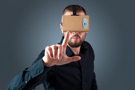 Excited young man using a VR headset glasses and experiencing virtual reality on grey blue background