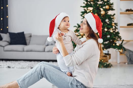 Holiday mood. Mother with her little daughter is indoors at home together.