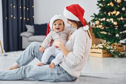 Holiday mood. Mother with her little daughter is indoors at home together.