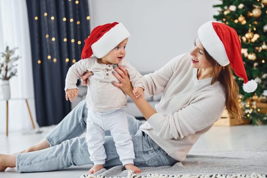 Celebrating Christmas. Mother with her little daughter is indoors at home together.