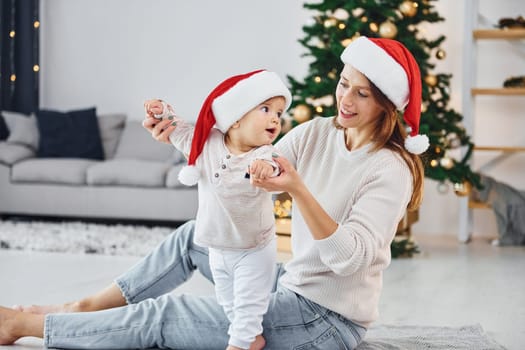 Celebrating Christmas. Mother with her little daughter is indoors at home together.