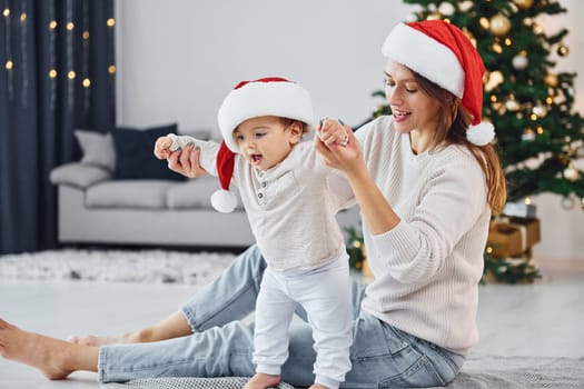 Celebrating Christmas. Mother with her little daughter is indoors at home together.