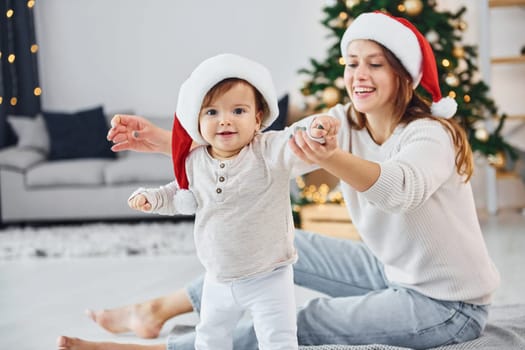 Celebrating Christmas. Mother with her little daughter is indoors at home together.