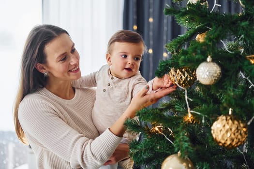 Mother with her little daughter is indoors at home together.