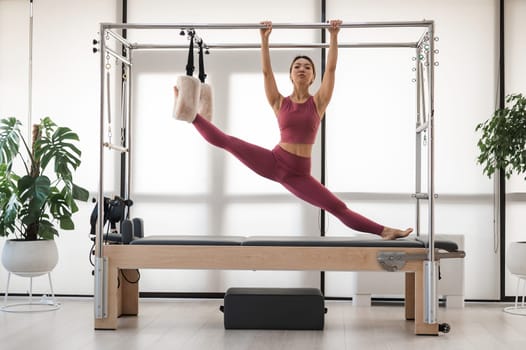 Beautiful asian woman doing splits on a reformer