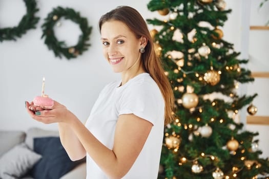 Christmas mood. Young woman in casual clothes is indoors in domestic room.