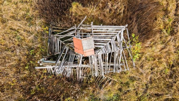 Top view of the plank roof of a ruined house. A wooden abandoned building stands alone in a vacant lot. Photograph of ruins that evoke longing and sadness.