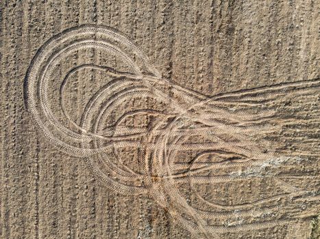 Top view of the tracks from the wheels of tractors after the harvest. An abstract pattern created by agricultural machinery on the ground. A circular pattern left behind by a vehicle.