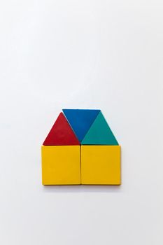 Small house of colorful figures on a white magnetic board. A structure consisting of triangles and squares in red, blue, green and yellow. There is empty copy space.