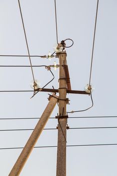 Electricity concept, concrete pole with high voltage wires on insulators. Close-up against the blue sky. Power line close to high voltage transformer station.