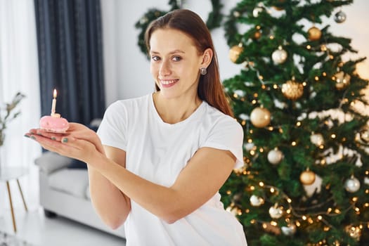 Christmas mood. Young woman in casual clothes is indoors in domestic room.