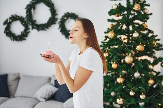 Christmas mood. Young woman in casual clothes is indoors in domestic room.