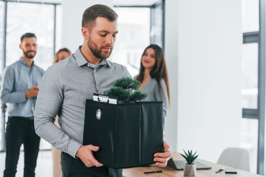 Man holding package. Group of business people that working on the project in the office.