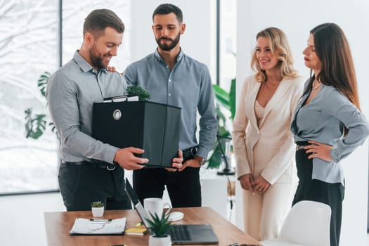 Man holding package. Group of business people that working on the project in the office.