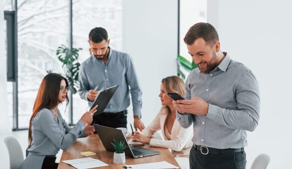 Man with phone. Group of business people that working on the project in the office.