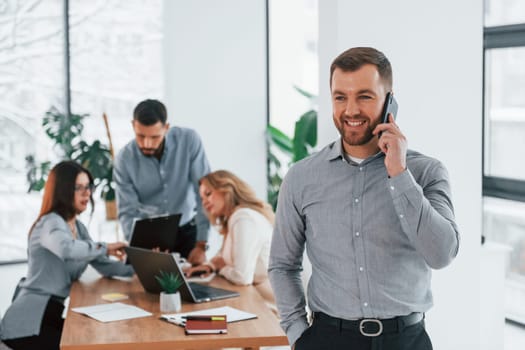 Man with phone. Group of business people that working on the project in the office.