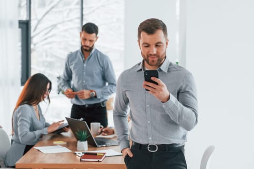 Man with phone. Group of business people that working on the project in the office.