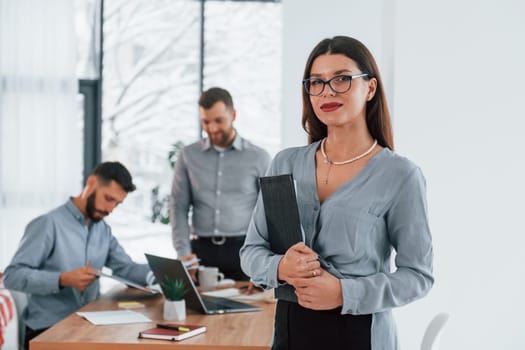 Woman standing in front of her employees. Group of business people that working on the project in the office.