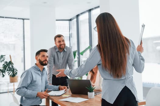 Woman standing in front of her employees. Group of business people that working on the project in the office.