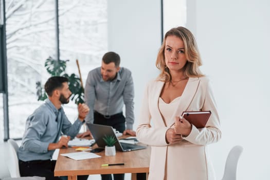 Woman in white clothes standing in front of her employees. Group of business people that working on the project in the office.