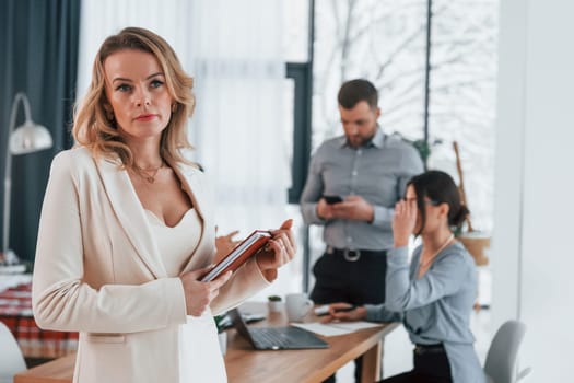 Woman in white clothes standing in front of her employees. Group of business people that working on the project in the office.