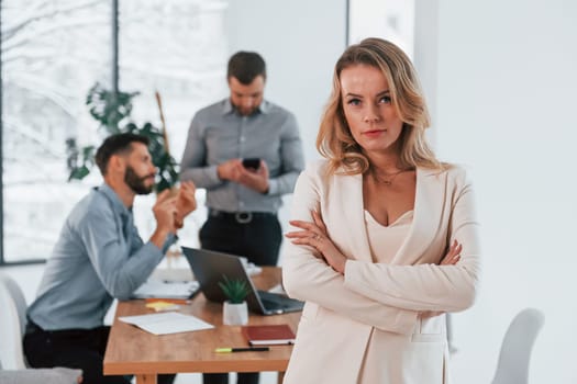 Woman in white clothes standing in front of her employees. Group of business people that working on the project in the office.