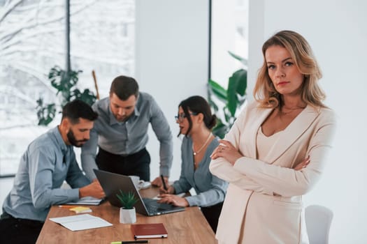 Woman in white clothes standing in front of her employees. Group of business people that working on the project in the office.