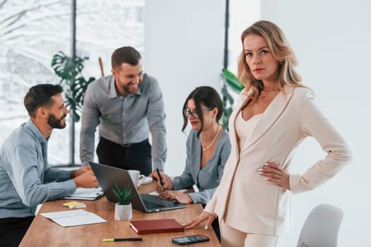 Woman looking at the camera. Group of business people that working on the project in the office.