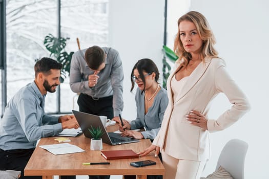 Woman looking at the camera. Group of business people that working on the project in the office.
