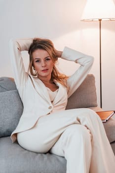 Sitting on the sofa. Business woman in formal clothes is indoors posing for the camera.