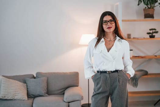 Business woman in formal clothes is indoors posing for the camera.