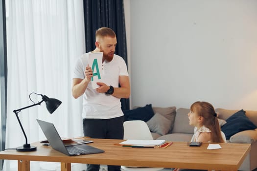 Learning letters. Father with his little daughter is at home together.