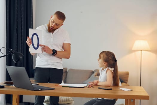Learning letters. Father with his little daughter is at home together.