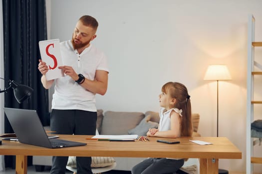 Learning letters. Father with his little daughter is at home together.