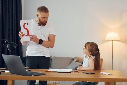 Learning letters. Father with his little daughter is at home together.